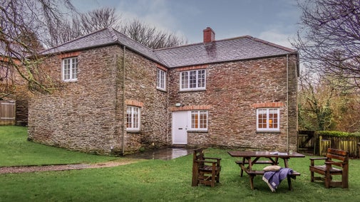 The exterior of Roseland Porth Barn and its lawned garden with outdoor dining furniture, Cornwall